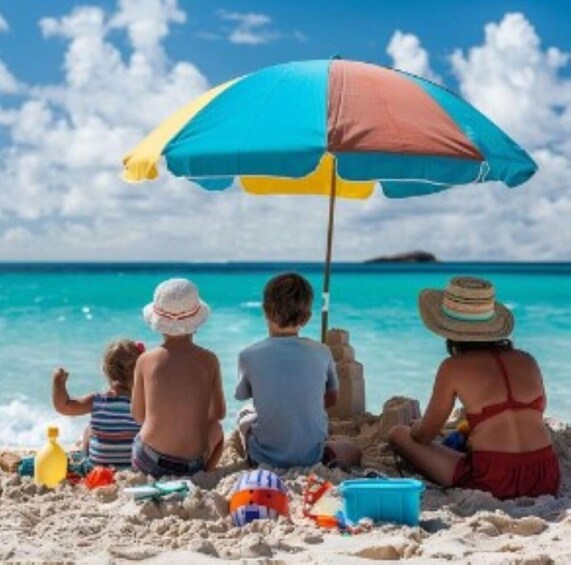 A family on a beach with a colorful umbrella, children playing with sand toys, and the ocean in the background. 1