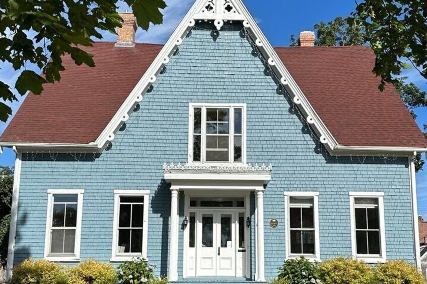 A blue house with a white door, two windows on the upper floor, and a red roof. 3