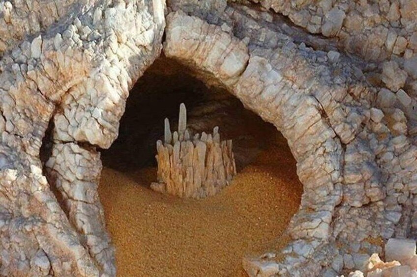 A cave entrance with a pile of rocks and sand inside. 5