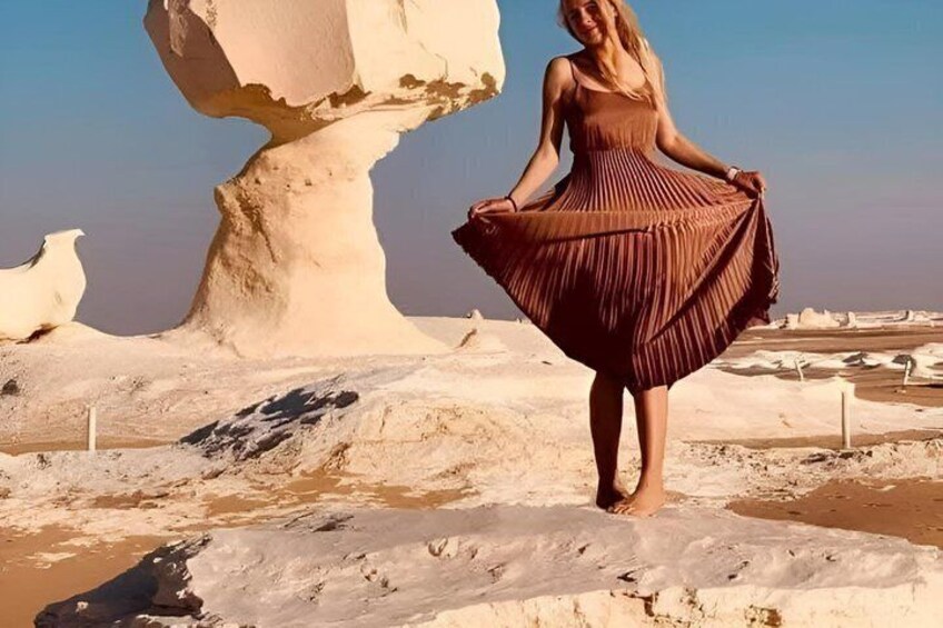A person standing on a sandy beach with white rock formations in the background. 3