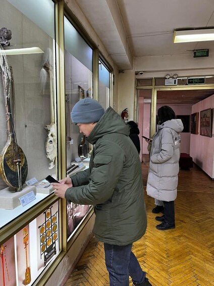 A person examining items in a display case at a museum or shop. 3