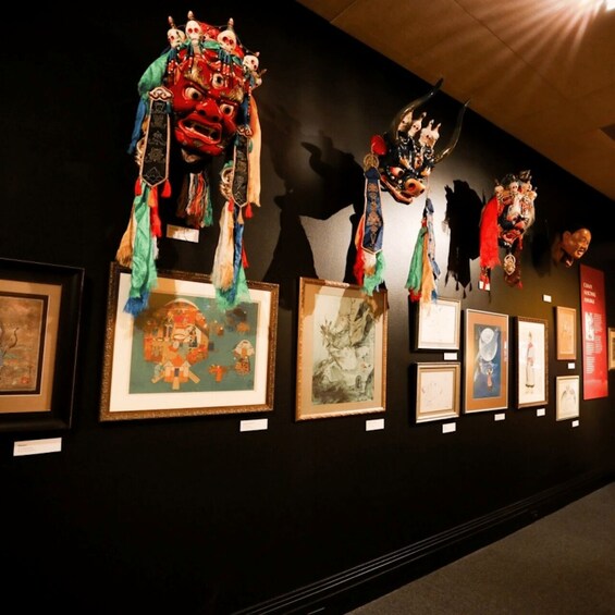 A wall with various framed artworks and traditional masks. 2
