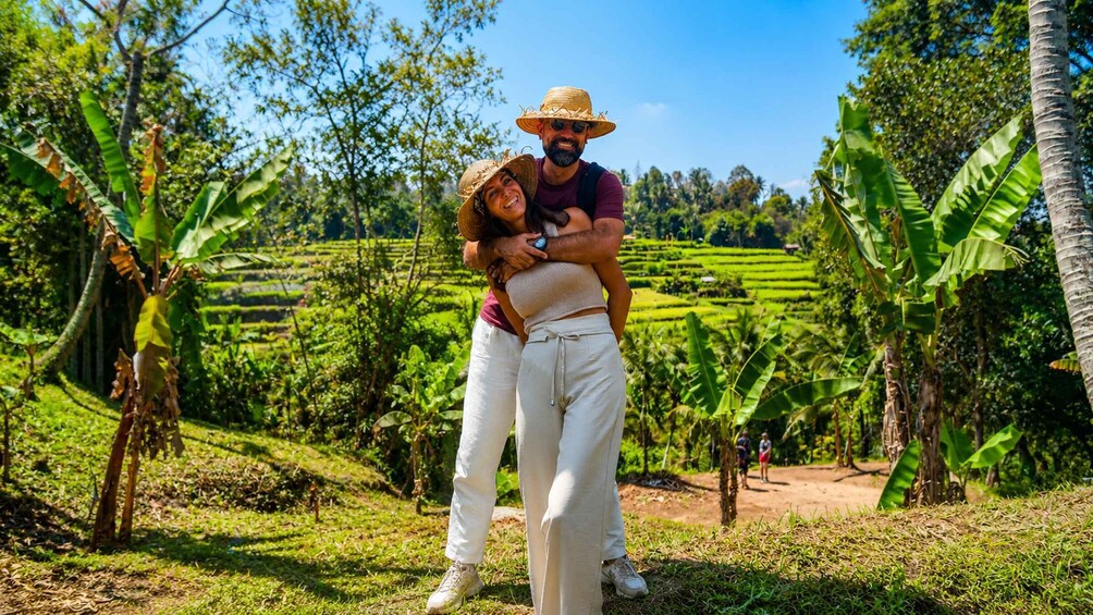 A couple embracing in a lush, green landscape with terraced fields and banana trees. 3