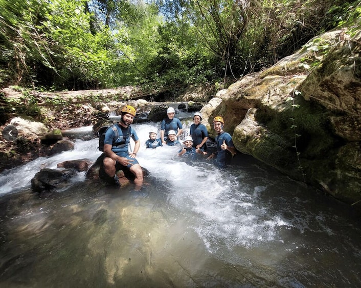 A group of people in a forested area near a flowing stream. 4