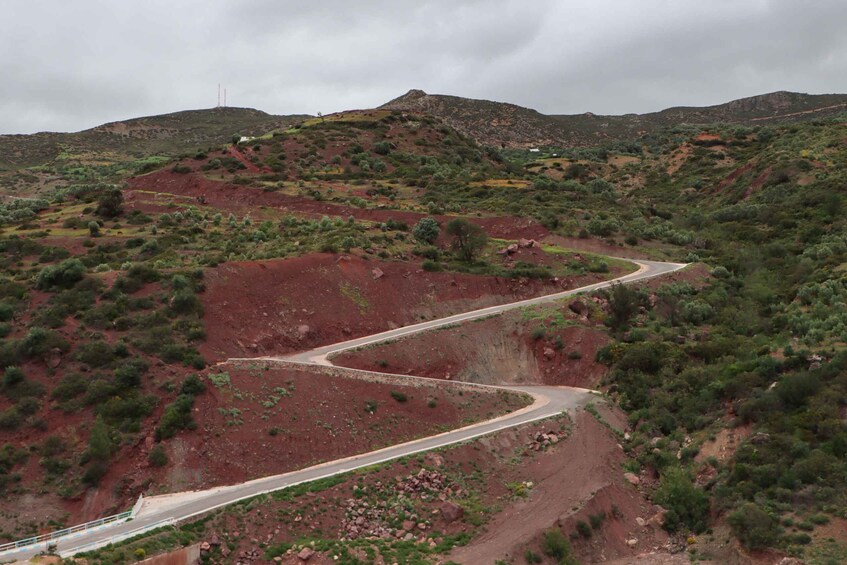 A winding mountain road with sparse vegetation and rocky terrain. 3