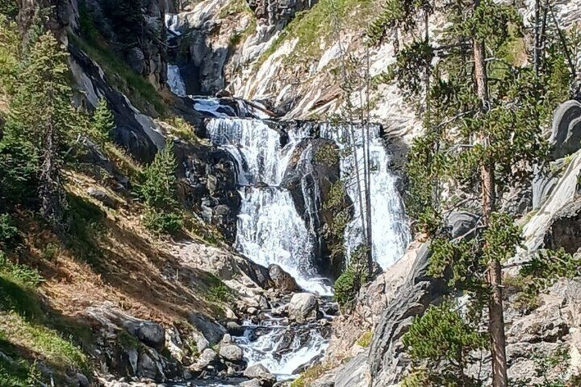 A waterfall cascading down a rocky cliff surrounded by trees. 3