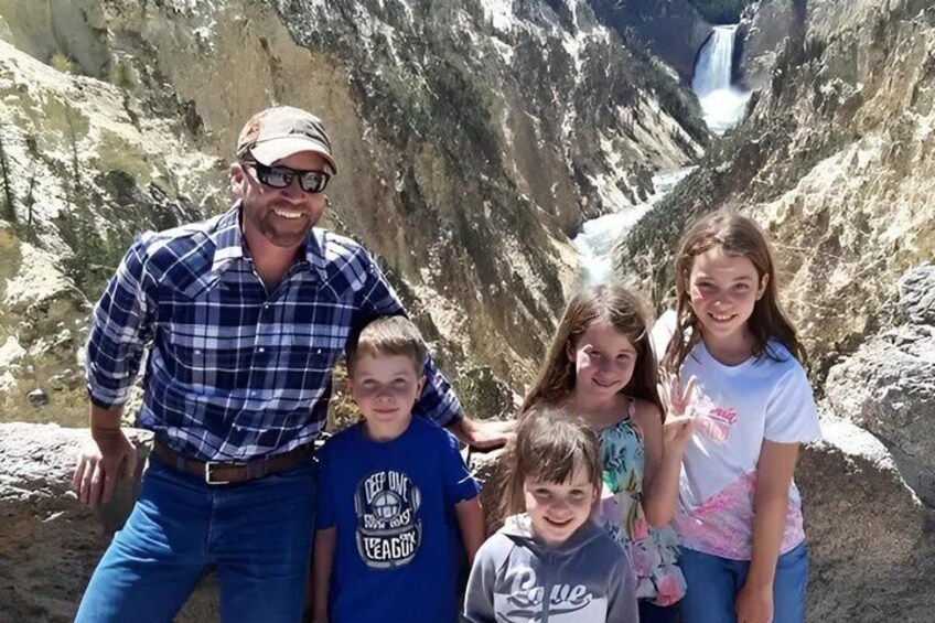 A family of five posing in a canyon with a waterfall in the background. 2