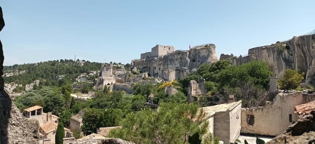 A historic town with ancient ruins, a prominent castle on a cliff, and surrounding greenery. 3