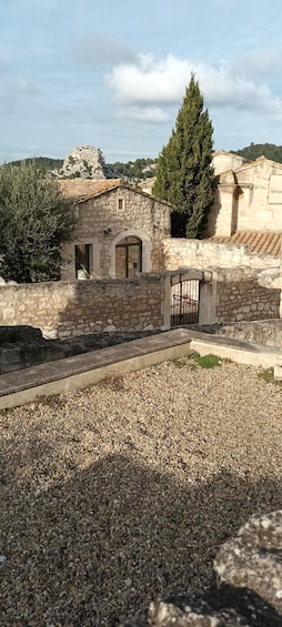 A stone building with a tiled roof, a gate, and a rocky hill in the background. 4