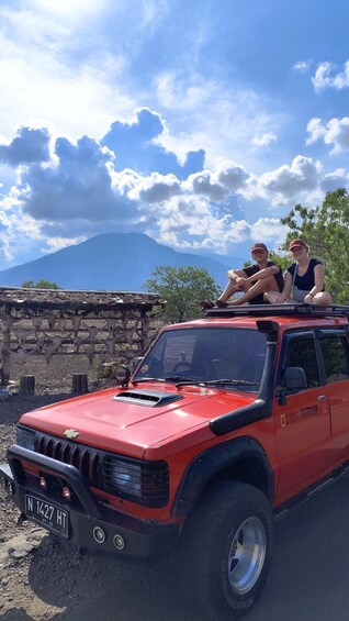 A red Chevrolet truck parked on a dirt road with a mountainous landscape in the background. 2