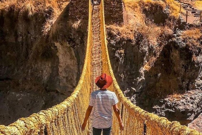 A person walking on a rope bridge over a canyon. 4