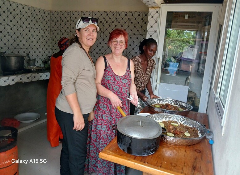 Three people serving food in a kitchen with tiled walls and a window. 1