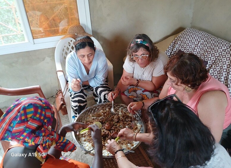 A group of people sitting around a table with a large bowl of food, possibly a communal meal. 2