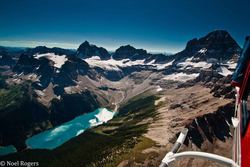 A mountainous landscape with a turquoise lake, snow-capped peaks, and a red vehicle in the foreground. 5