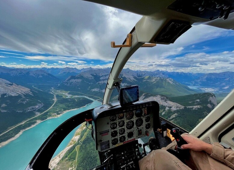 A helicopter cockpit with a view of a mountainous landscape and a river below. 3