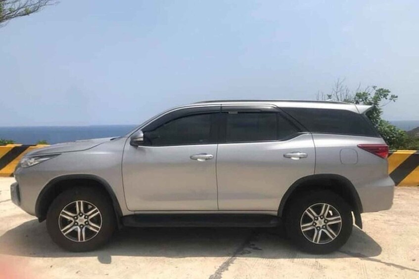 A silver SUV parked on a concrete surface with a clear sky and distant landscape in the background. 5