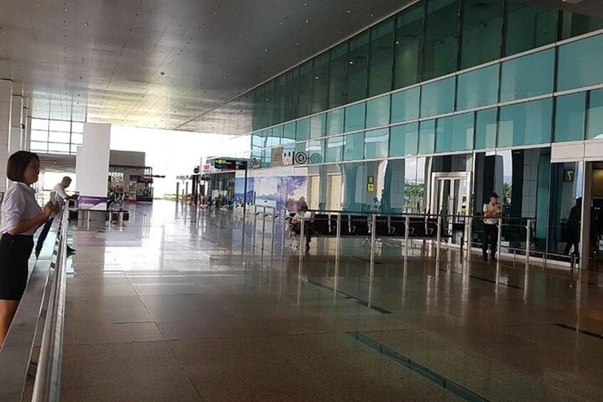A spacious indoor area with a glass wall, a metal railing, and a few people. 2