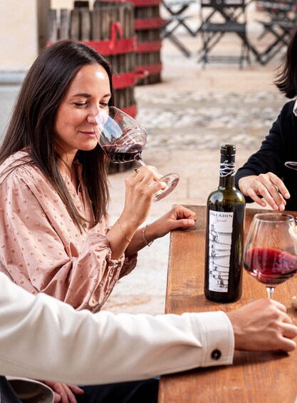 A person holding a wine glass, a bottle of wine, and a wooden table. 2