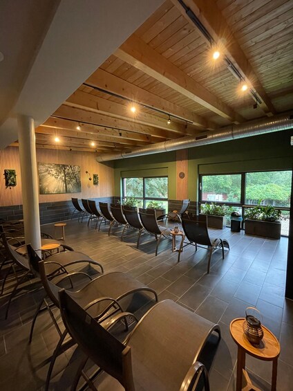 A modern indoor seating area with wooden beams, large windows, and potted plants. 3