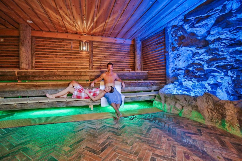 A wooden sauna with a stone wall and a herringbone floor. 1