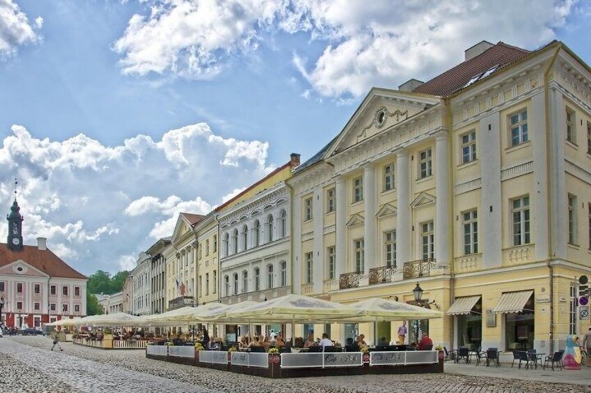 A historic building with classical architecture, a cobblestone street, and outdoor seating areas. 2
