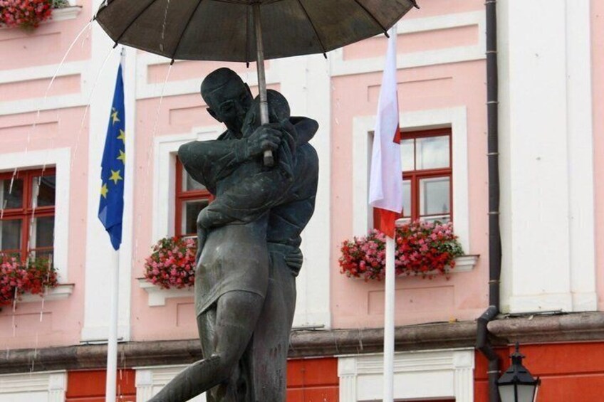 A statue of a man holding a child, with flags in the background. 3