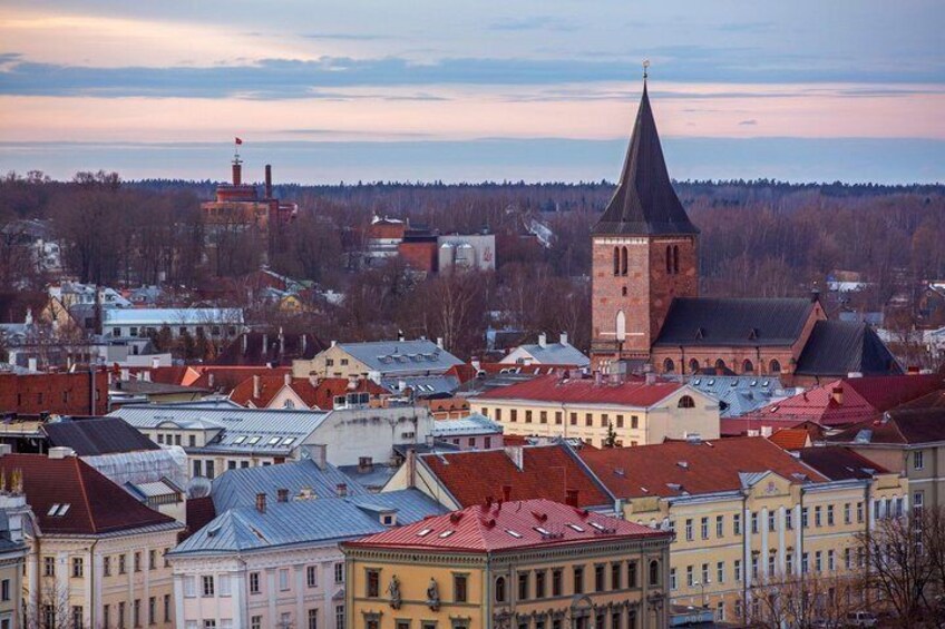 A town with historic buildings, a prominent church with a tall spire, and a river in the background. 1