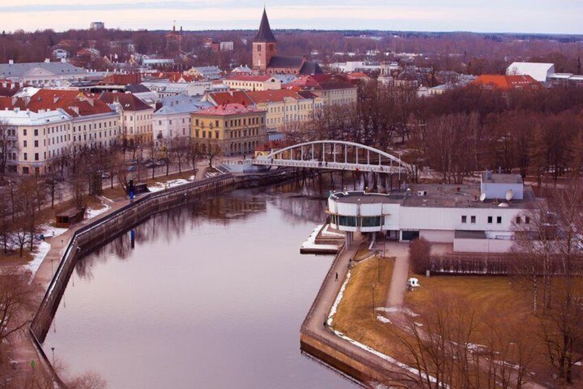A river with a bridge, buildings, and a tower. 4