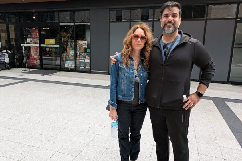 Two people standing in front of a building with glass doors and windows. 3