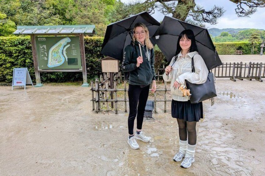 Two people holding umbrellas, a map sign, and a wooden fence in a park. 5