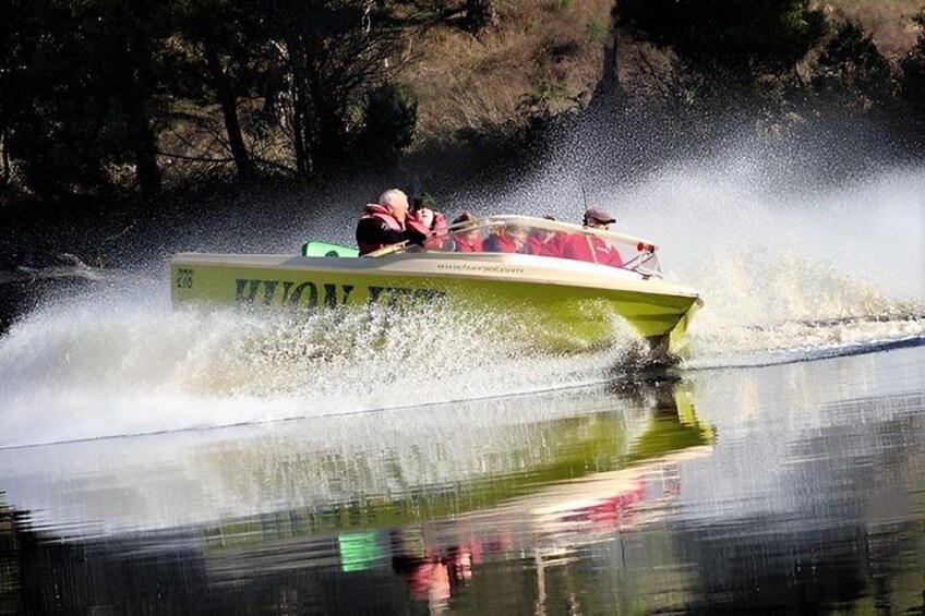 A speedboat with a green hull and a number 276 sign, creating a large wake in the water. 5
