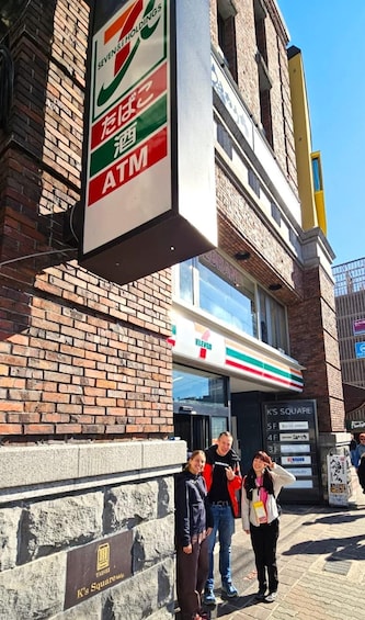 A 7-Eleven store with a sign for an ATM, a brick building, and a sign for K's Square. 5