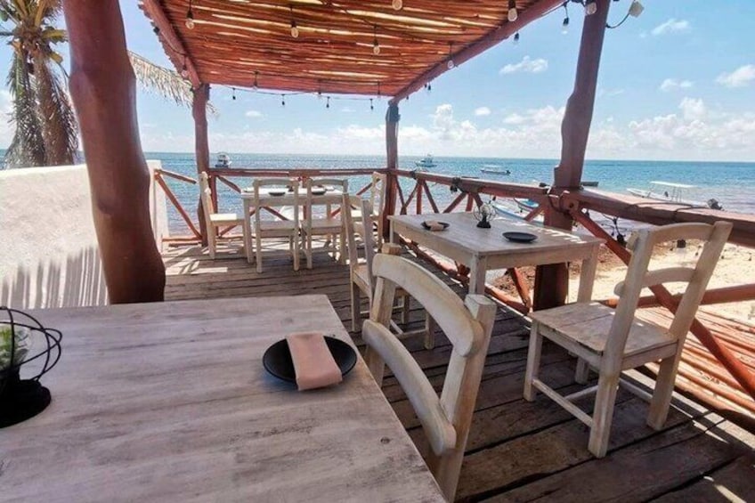 A wooden deck with tables and chairs overlooking the beach. 5