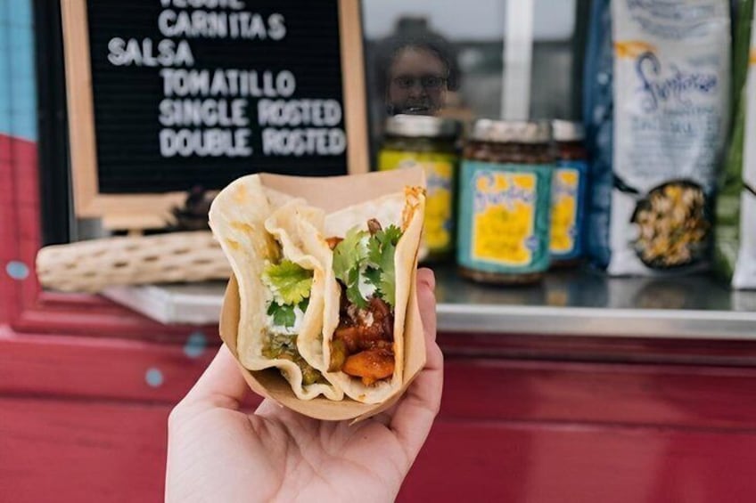 A hand holding a burrito with visible ingredients like lettuce and a filling. 1