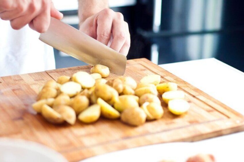 A person chopping potatoes on a wooden cutting board. 5