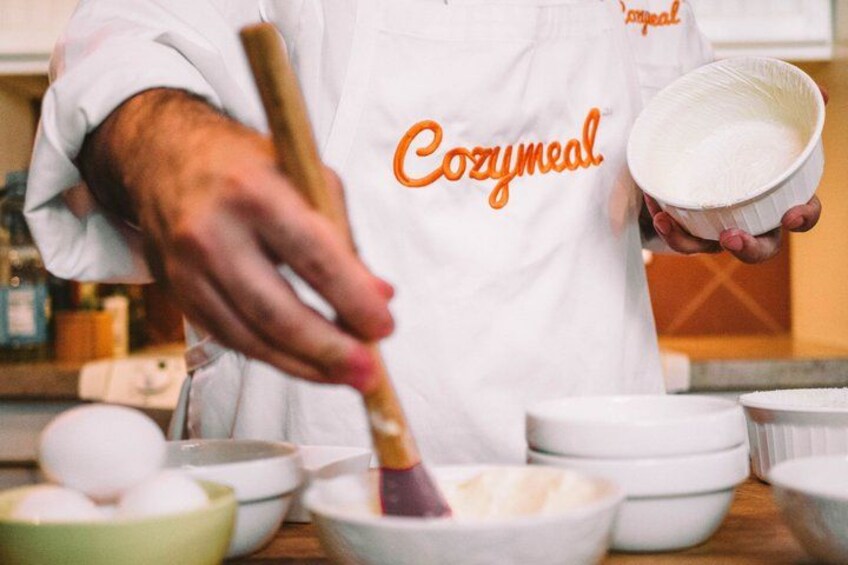 A person in a white apron with 'Cozymmeal' text, stirring a white substance in a bowl. 3