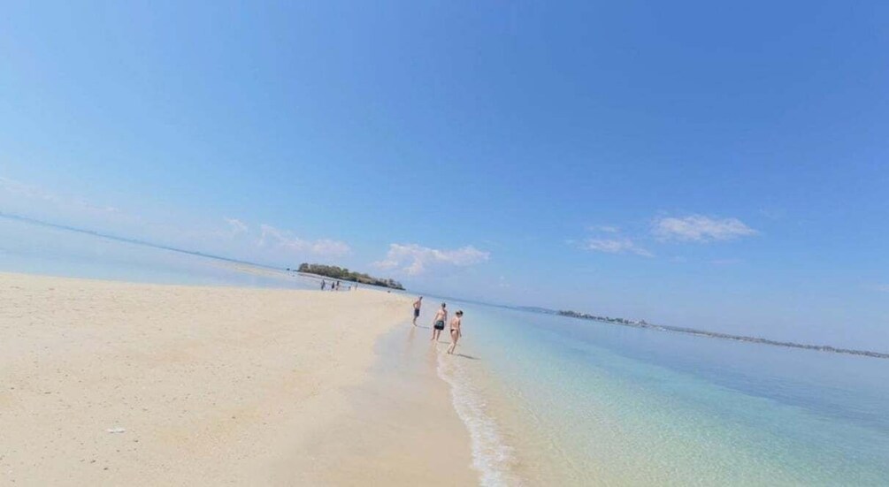 A beach with clear water and a distant island. 3