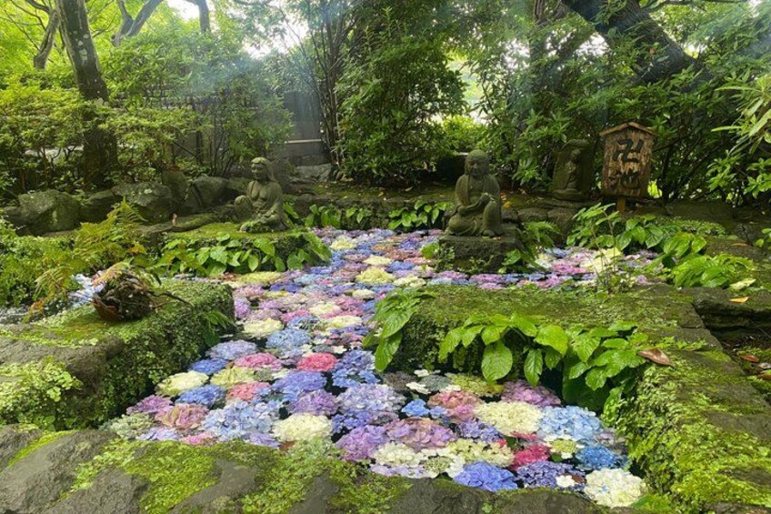 A garden with a stone pathway, statues, and a variety of flowers. 4