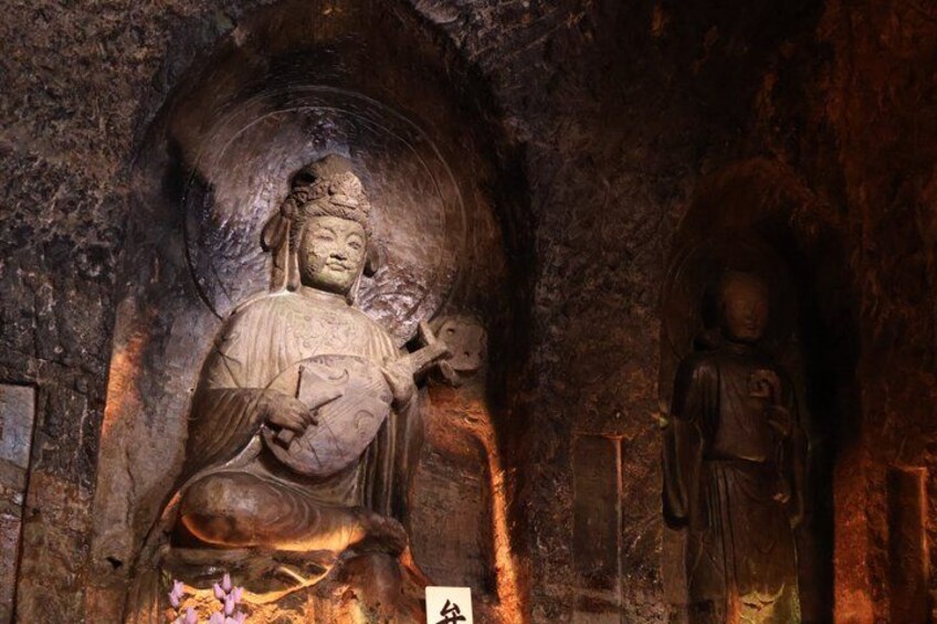 A large seated Buddha statue in a cave with a smaller statue beside it. 3