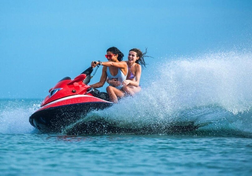 Deux personnes sur un jet ski qui soulèvent des éclaboussures dans l’eau. 1