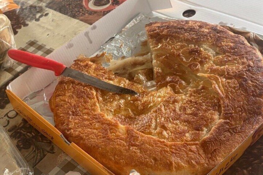 A round cake with a golden-brown crust in a cardboard box. 2