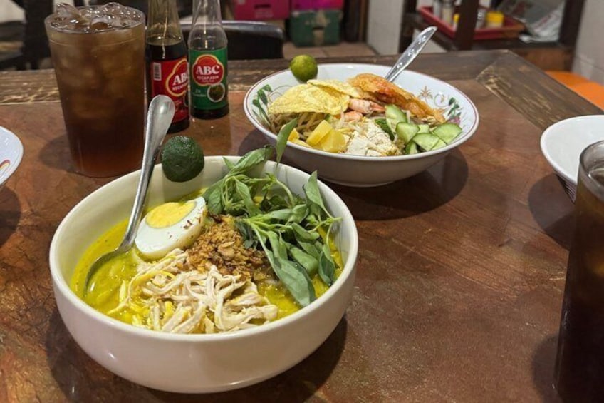 A table with two bowls of food, a bottle of soda, and a glass of iced tea. 5