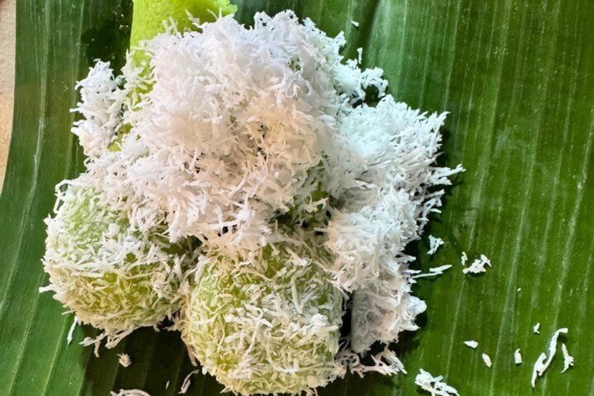 A bunch of round, white-coated food items on a green leaf. 2