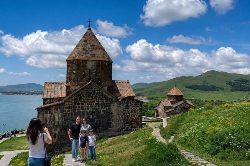 A stone church with a bell tower, a pathway, and a lake in the background. 1