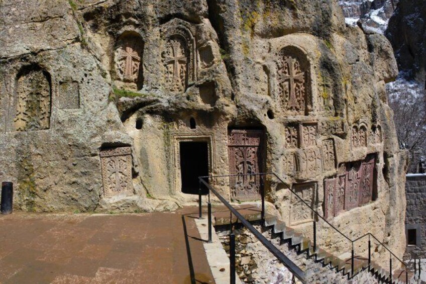 A rock-cut church with intricate carvings and a staircase leading to an entrance. 5