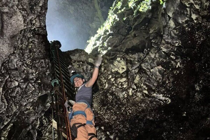 A person climbing a rocky terrain with a metal ladder. 1