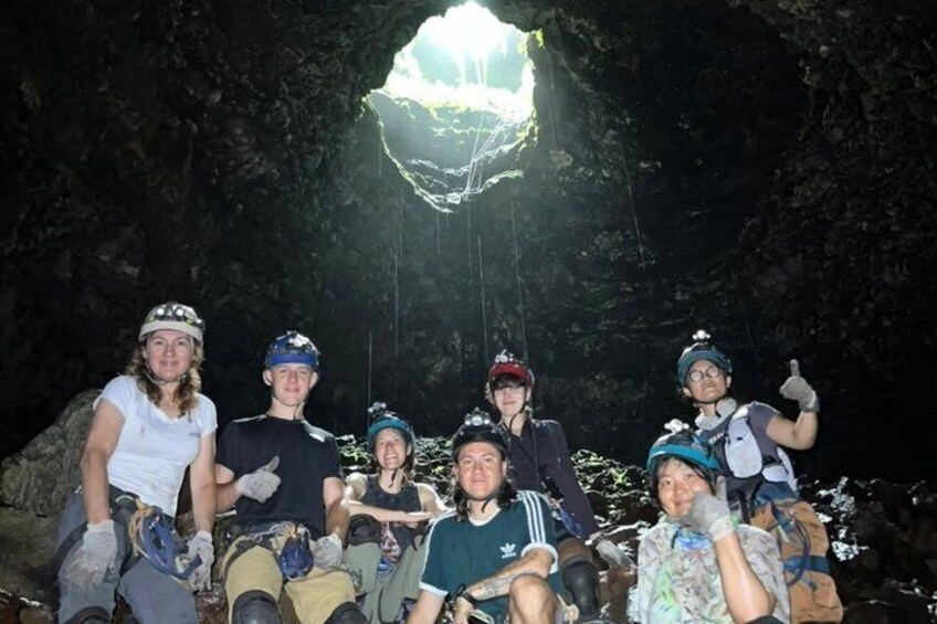 A group of people sitting in a cave with a large crystal formation above them. 3