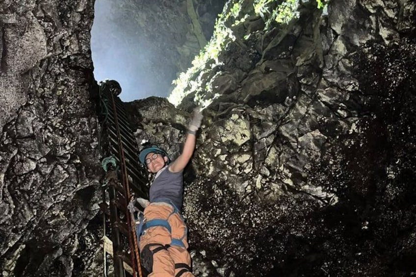 A person climbing a rocky terrain with a metal ladder. 1