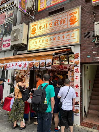 A street food stall with a signboard advertising 'Shanghai Fried Dumpling.' People are queuing outside. 4