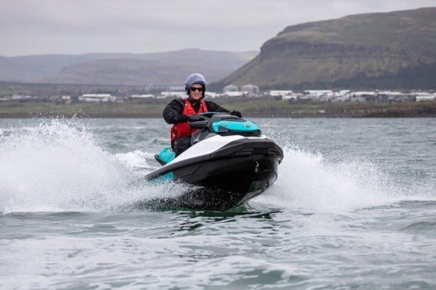A person riding a jet ski on a body of water with mountains in the background. 3